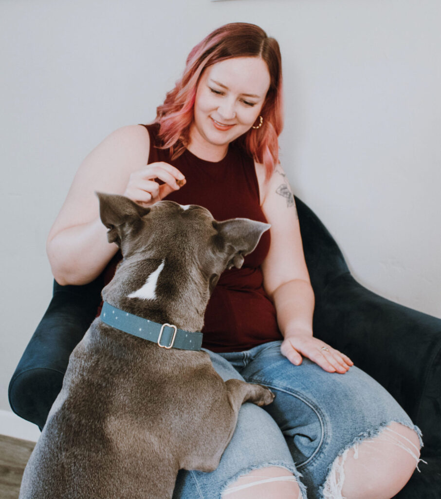 A women smiling while feeding dog a treat